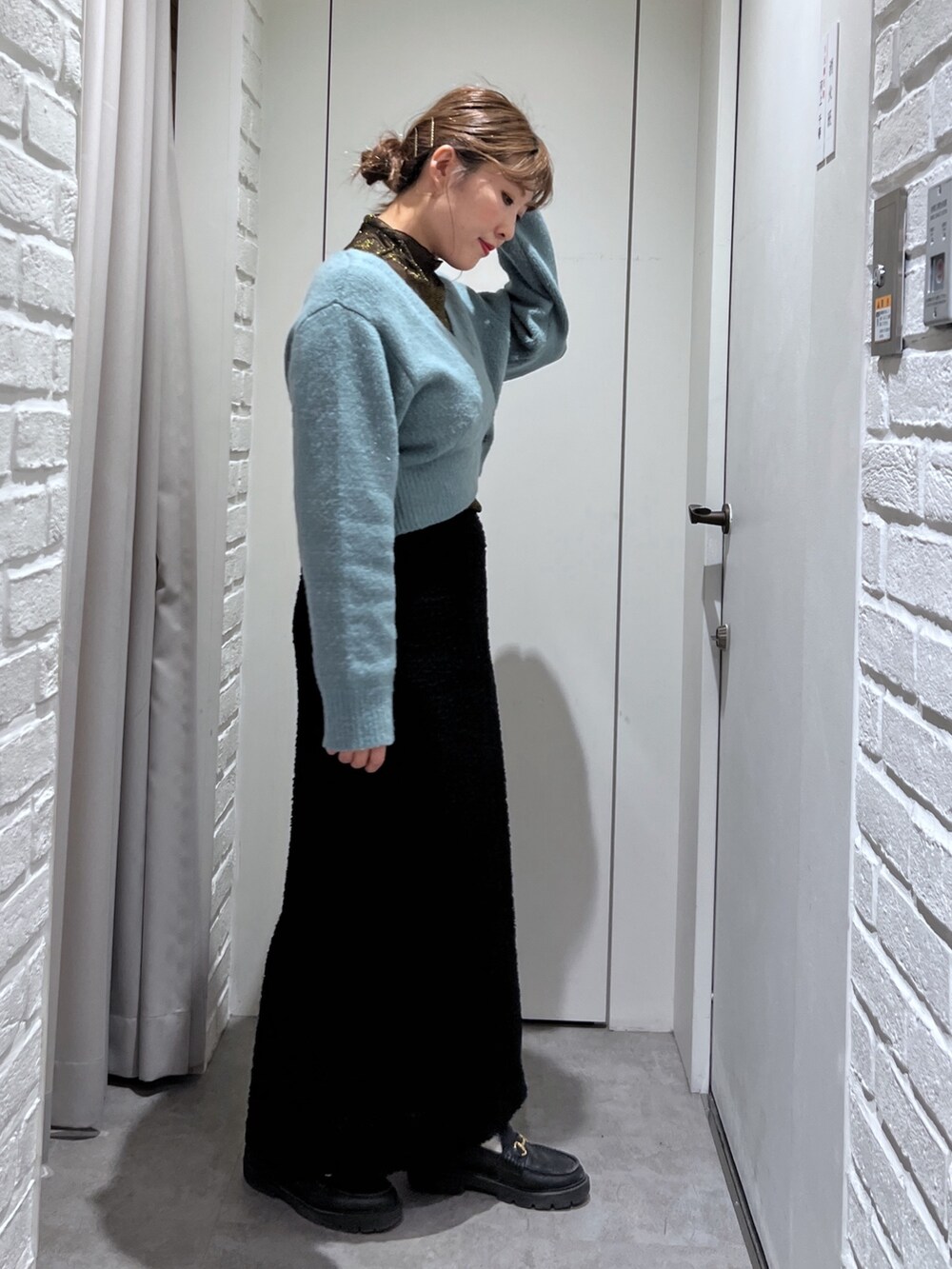 ブラック系のスカート、グリーン系のニット/セーター、ブラック系のTシャツ/カットソーを着用したレディースの秋コーディネートの3枚目の写真