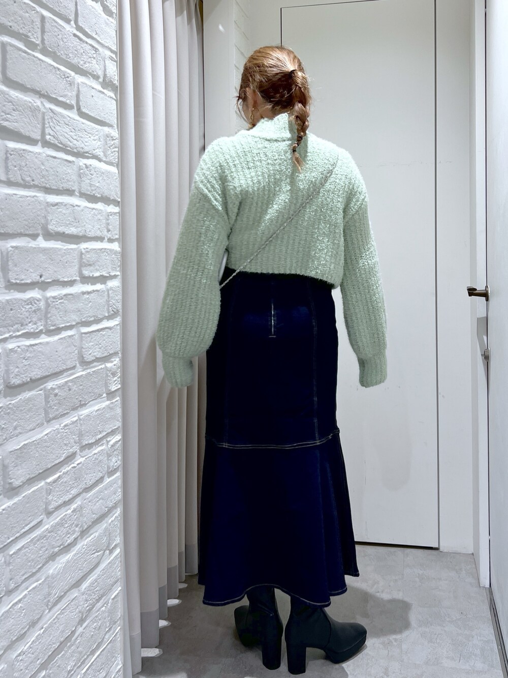 ブルー系のスカート、グリーン系のニット/セーター、シルバー系のショルダーバッグを着用したレディースの冬コーディネートの3枚目の写真