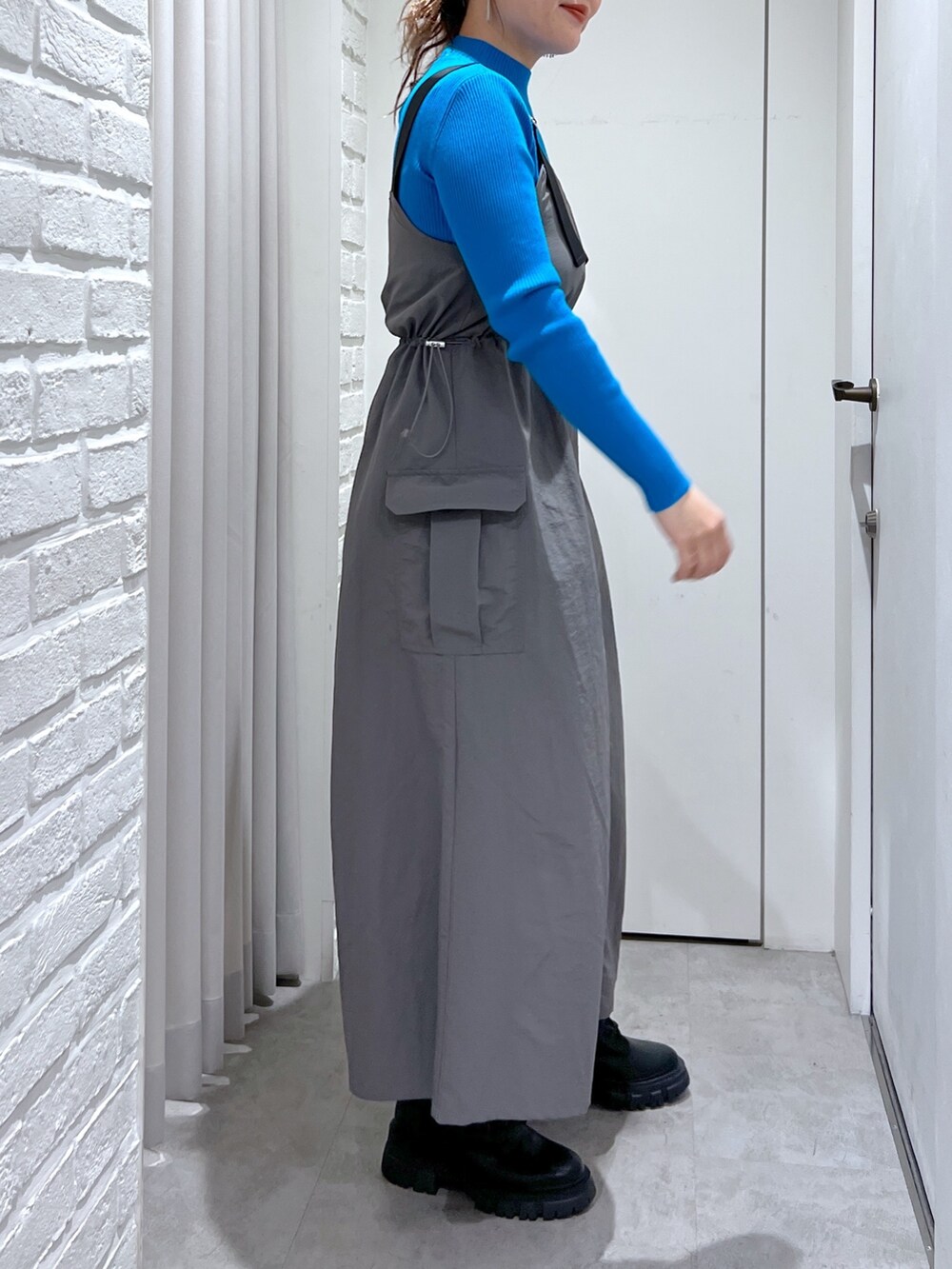 グレー系のワンピース、ブラック系のハンドバッグ、ブラック系のブーツを着用したレディースの冬コーディネートの5枚目の写真