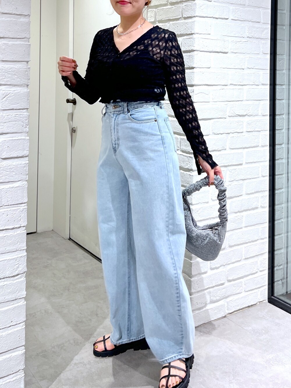 ブルー系のデニムパンツ、ブラック系のサンダル、シルバー系のハンドバッグを着用したレディースの夏コーディネートの5枚目の写真