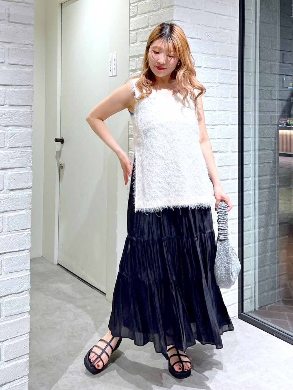 ホワイト系のシャツ/ブラウス、ブラック系のスカート、ブラック系のサンダルを着用したレディースの夏コーディネートの2枚目の写真