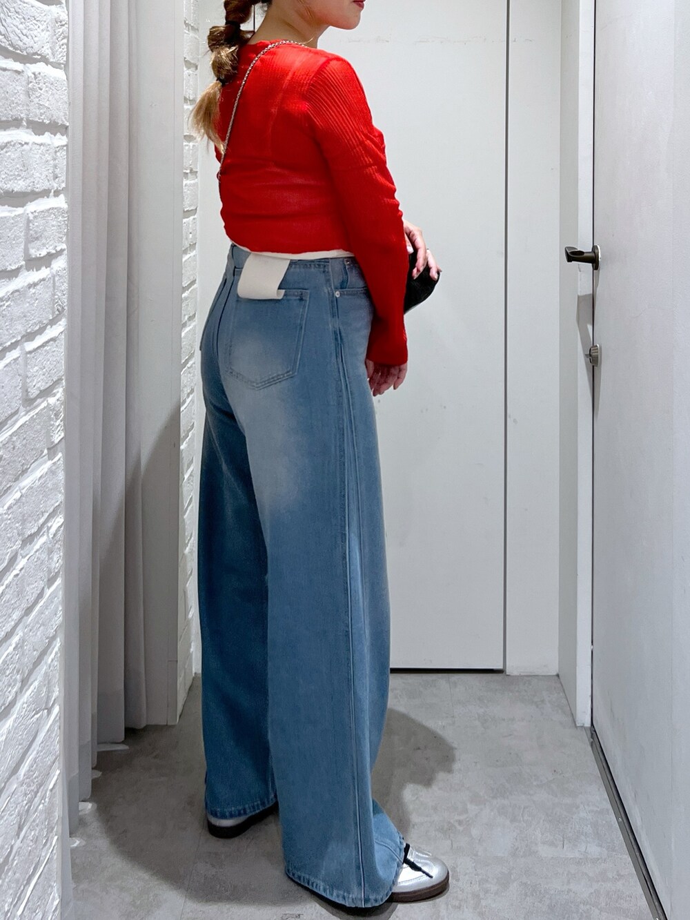 ブルー系のデニムパンツ、レッド系のカーディガン/ボレロ、ブラック系のショルダーバッグを着用したレディースの夏コーディネートの6枚目の写真