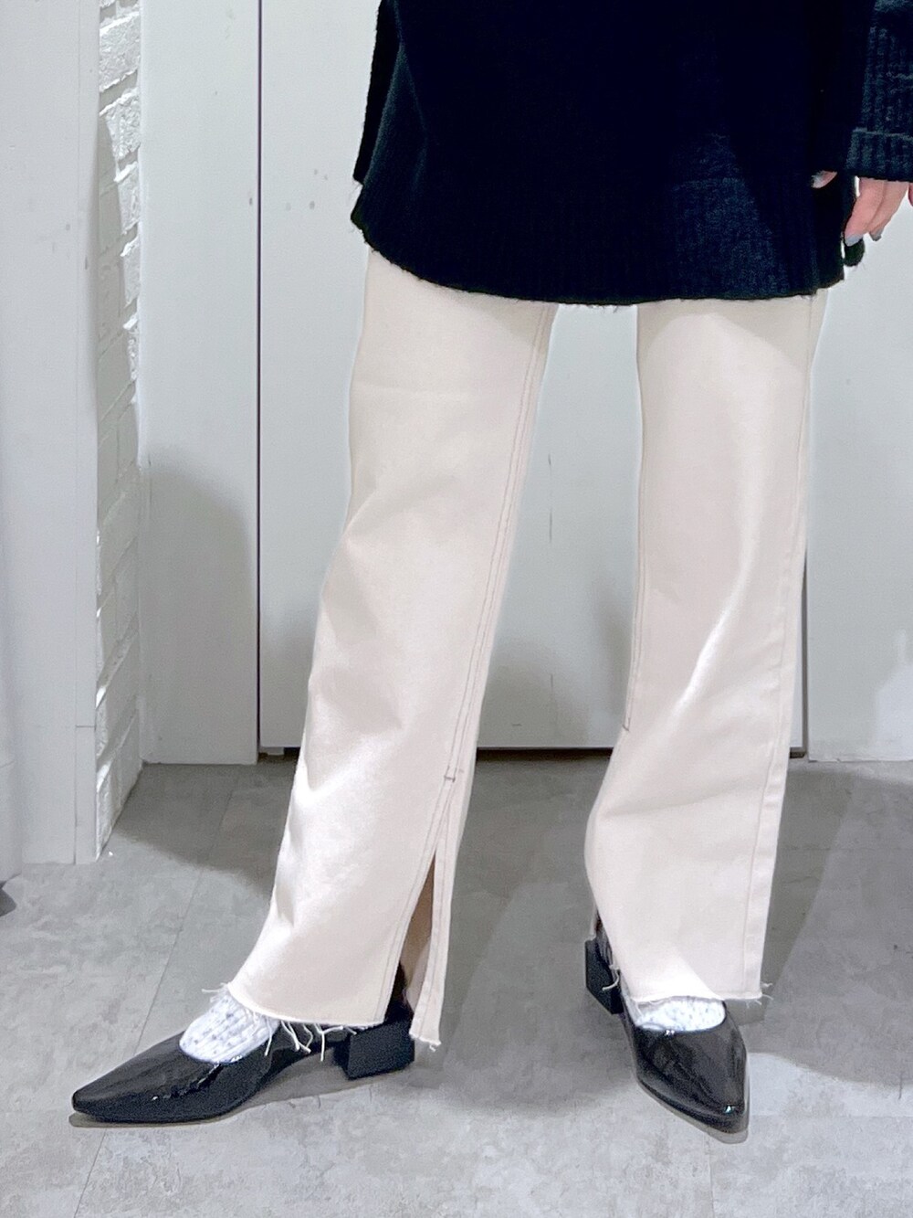 ブラック系のニット/セーター、ホワイト系のデニムパンツ、ブラック系のバレエシューズを着用したレディースの冬コーディネートの6枚目の写真