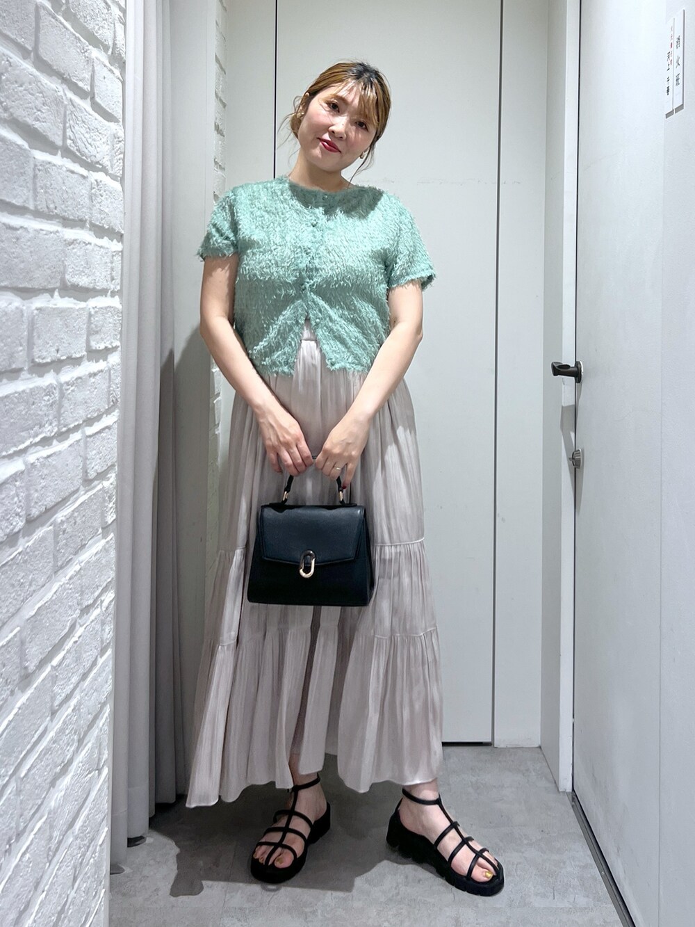 ホワイト系のスカート、グリーン系のシャツ/ブラウス、ブラック系のショルダーバッグを着用したレディースの夏コーディネートの2枚目の写真