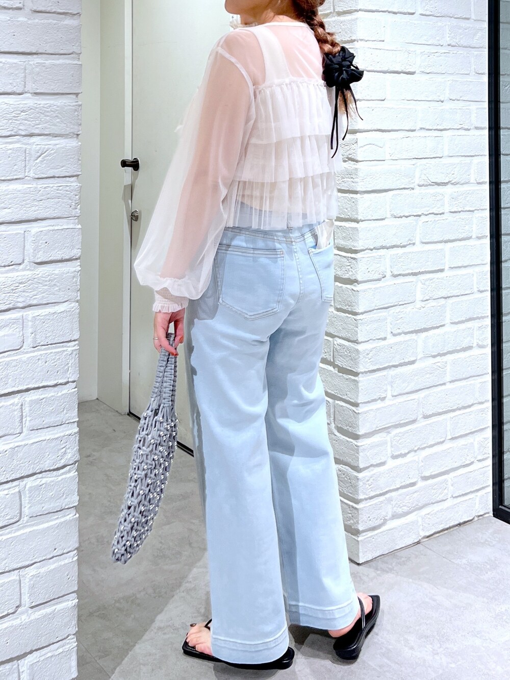 ブルー系のデニムパンツ、グリーン系のハンドバッグ、ホワイト系のシャツ/ブラウスを着用したレディースの夏コーディネートの6枚目の写真