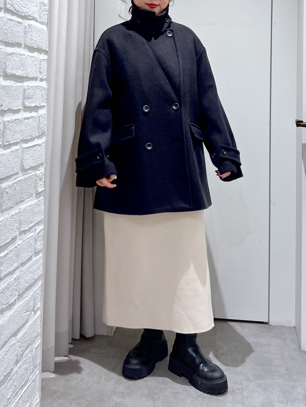 ブラック系のピーコート、ホワイト系のワンピース、ブラック系のTシャツ/カットソーを着用したレディースの冬コーディネートの4枚目の写真