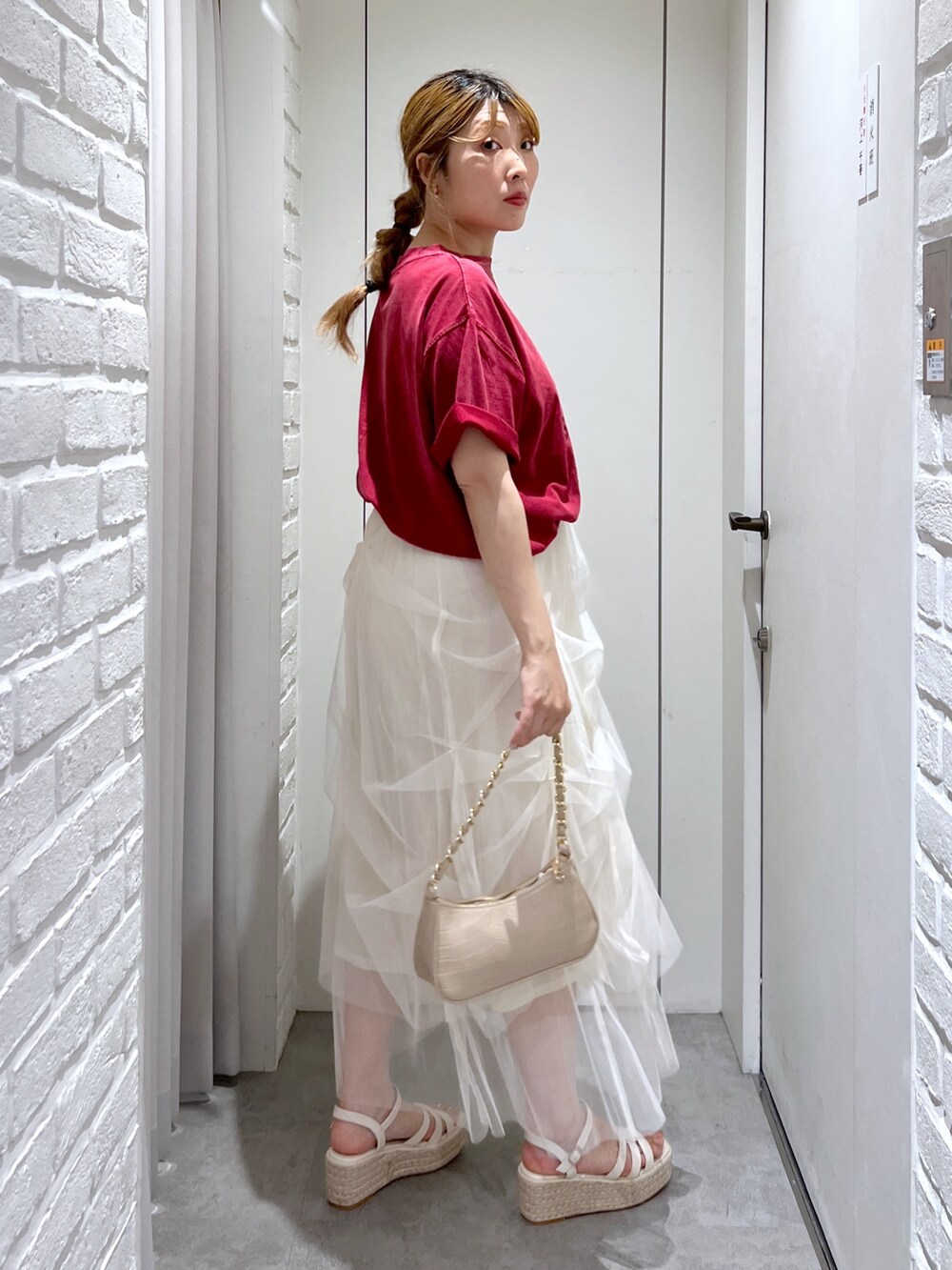 ホワイト系のスカート、レッド系のTシャツ/カットソー、ホワイト系のサンダルを着用したレディースの夏コーディネートの3枚目の写真