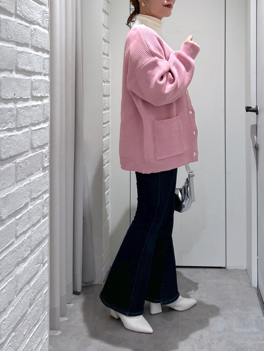 ブルー系のデニムパンツ、ホワイト系のパンプス、ブルー系のベストを着用したレディースの冬コーディネートの4枚目の写真