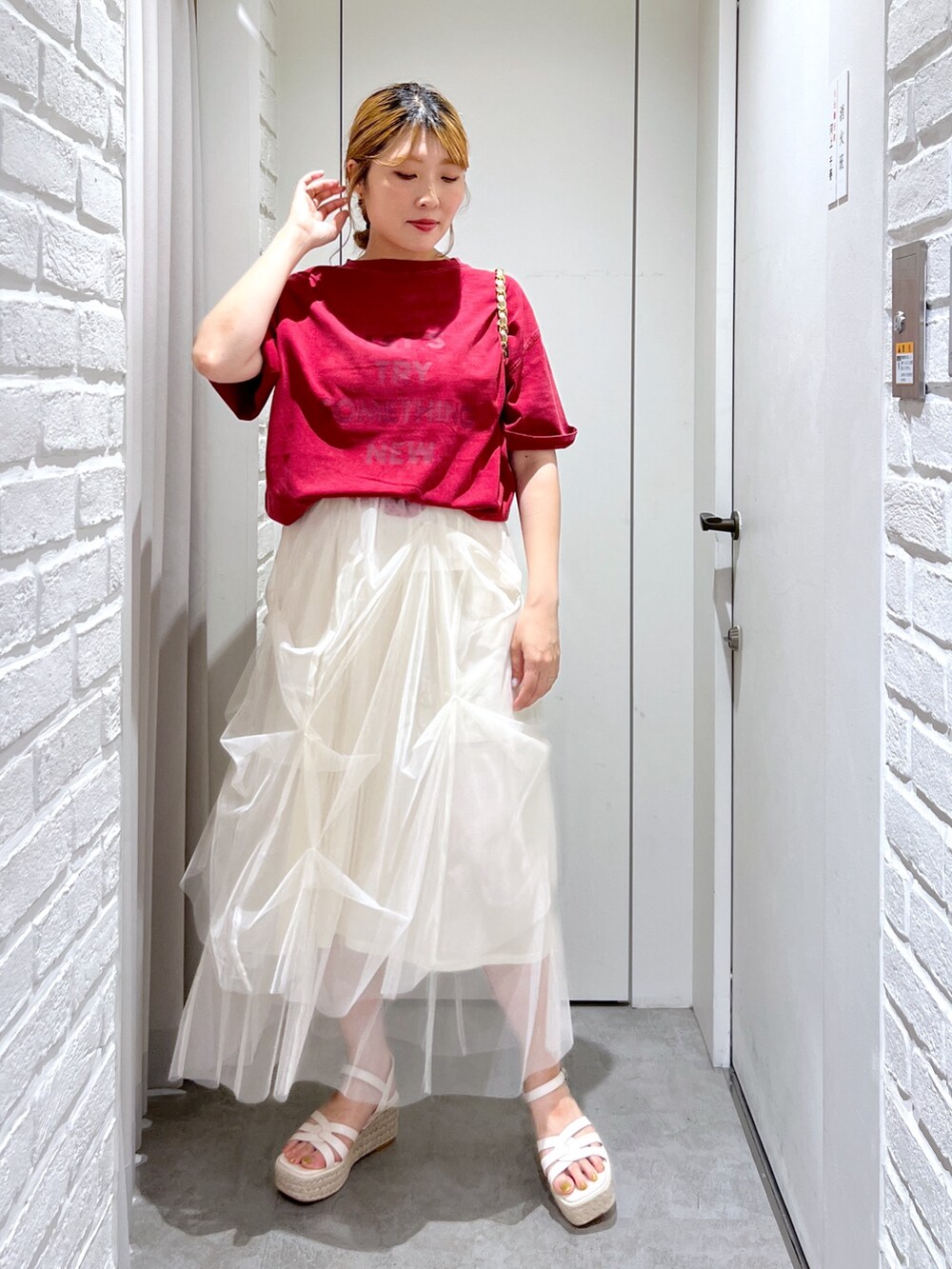 ホワイト系のスカート、レッド系のTシャツ/カットソー、ホワイト系のサンダルを着用したレディースの夏コーディネートの2枚目の写真