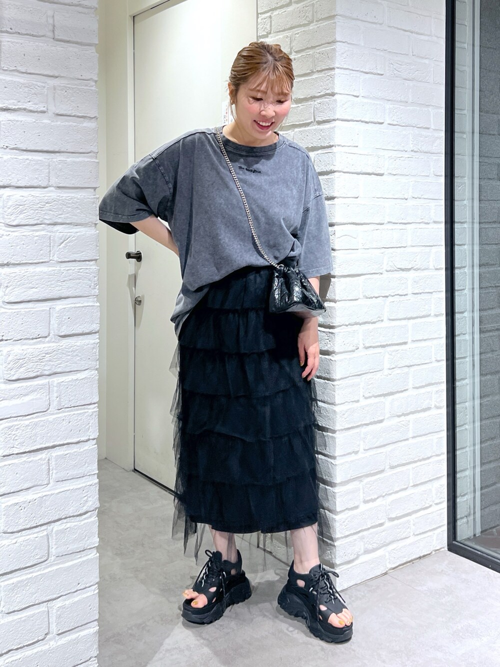 ブラック系のスカート、ブラック系のサンダル、ブラック系のショルダーバッグを着用したレディースの夏コーディネートの2枚目の写真