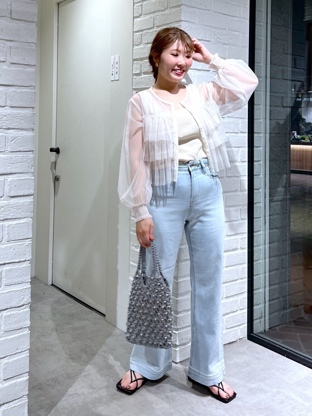 ブルー系のデニムパンツ、グリーン系のハンドバッグ、ホワイト系のシャツ/ブラウスを着用したレディースの夏コーディネートの2枚目の写真