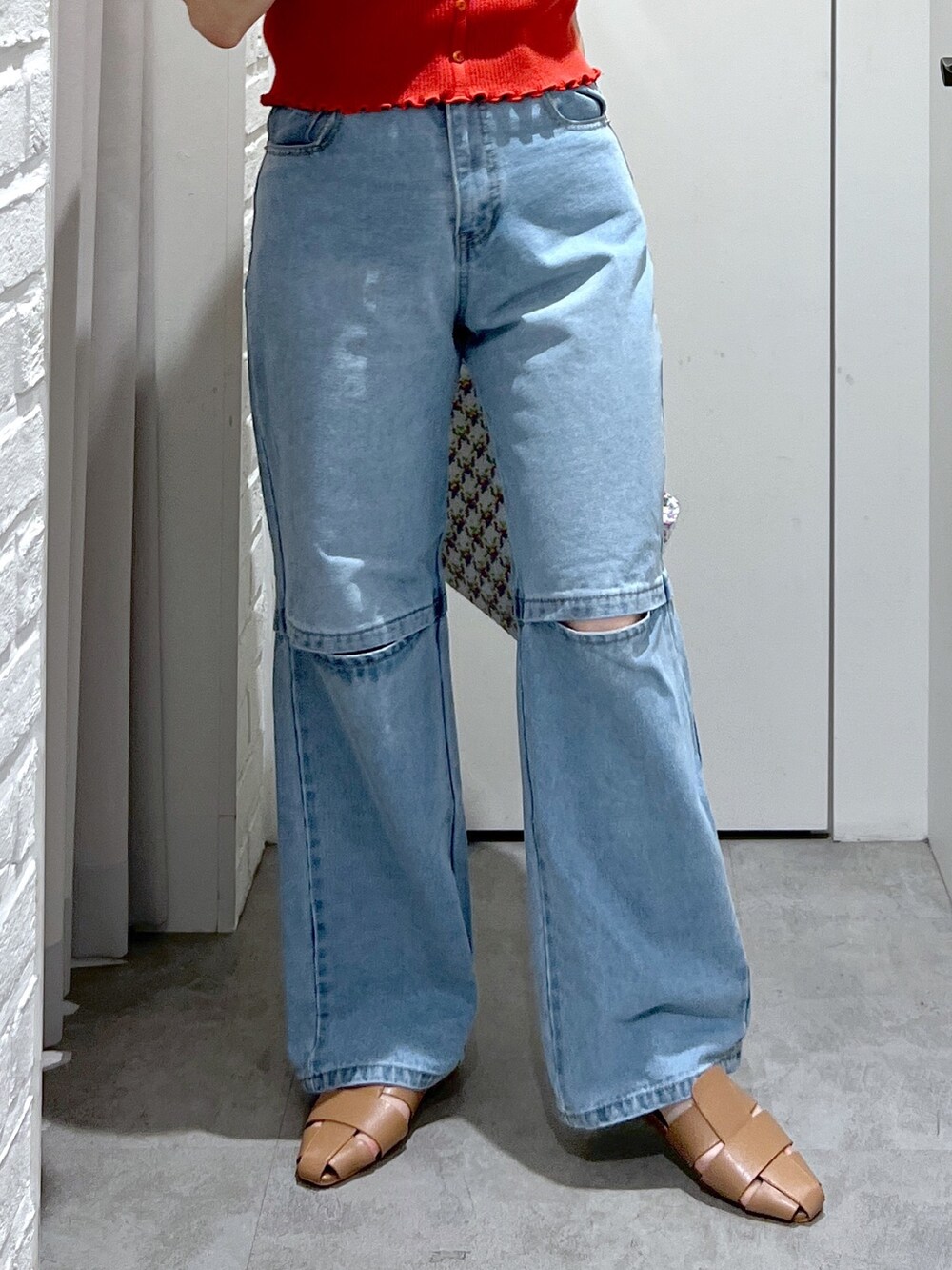 レッド系のニット/セーター、ブルー系のデニムパンツ、ベージュ系のスリッポンを着用したレディースの夏コーディネートの6枚目の写真