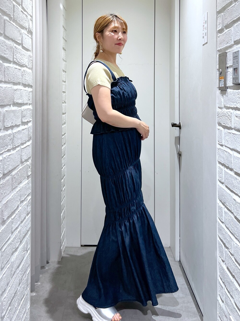 ブルー系のワンピース、イエロー系のニット/セーター、シルバー系のサンダルを着用したレディースの夏コーディネートの2枚目の写真