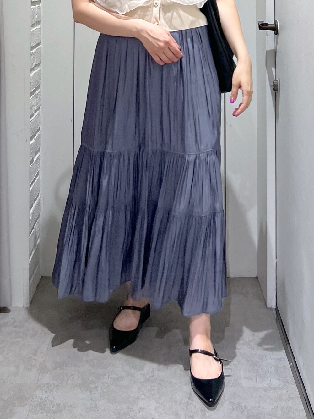 ブルー系のスカート、ホワイト系のベスト、ブラック系のパンプスを着用したレディースの夏コーディネートの7枚目の写真