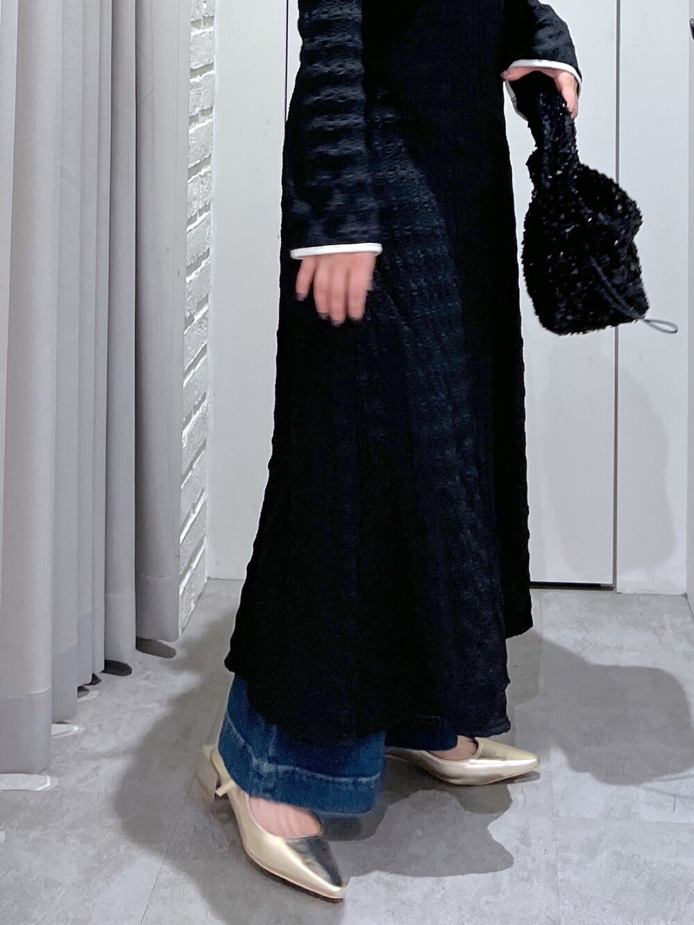 ブラック系のワンピース、ブルー系のデニムパンツ、ブラック系のハンドバッグを着用したレディースの春コーディネートの5枚目の写真