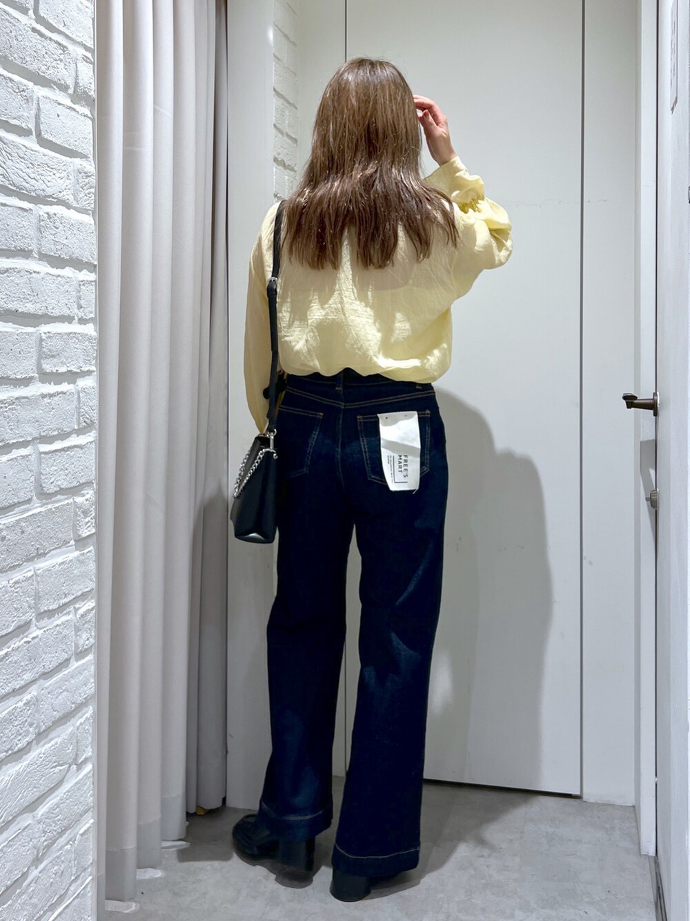 ブルー系のデニムパンツ、イエロー系のシャツ/ブラウス、ブラック系のショルダーバッグを着用したレディースの秋コーディネートの3枚目の写真