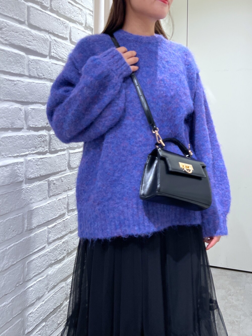 ブルー系のニット/セーター、ブラック系のショルダーバッグ、ブラック系のスカートを着用したレディースの秋コーディネートの5枚目の写真