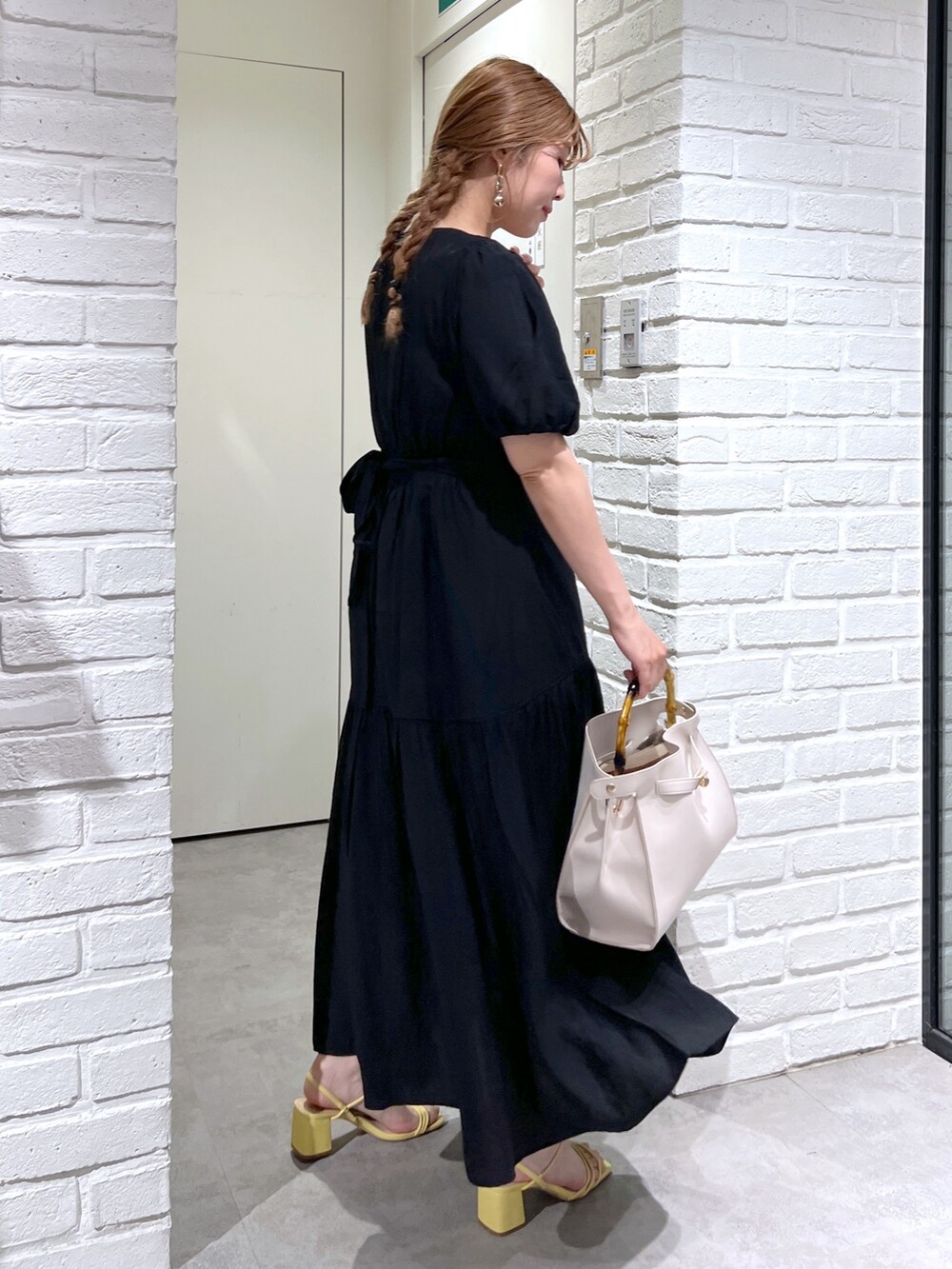ホワイト系のショルダーバッグ、ブラック系のワンピース、イエロー系のサンダルを着用したレディースの夏コーディネートの3枚目の写真