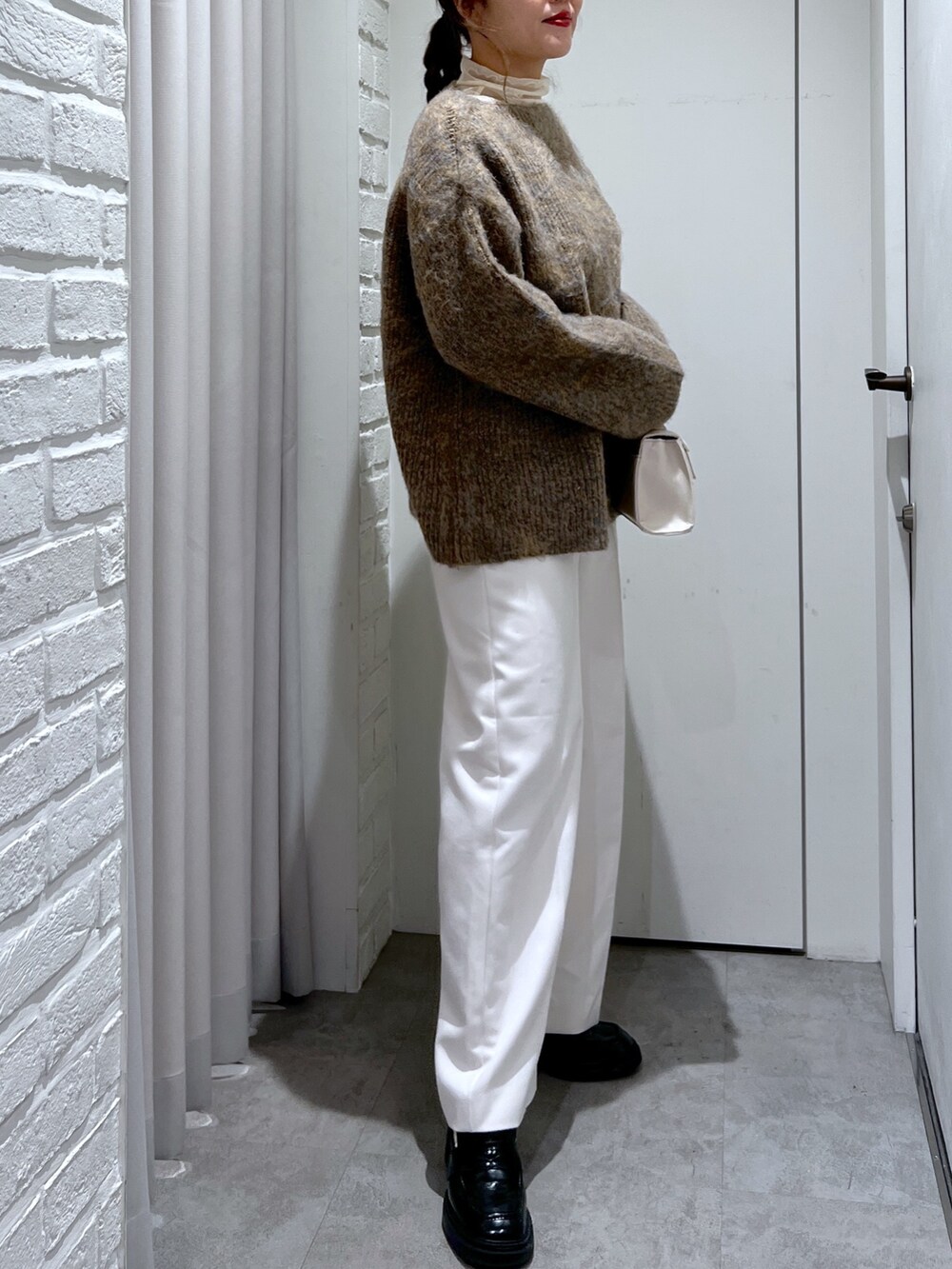 ベージュ系のニット/セーター、ホワイト系のスラックス、ホワイト系のショルダーバッグを着用したレディースの冬コーディネートの5枚目の写真