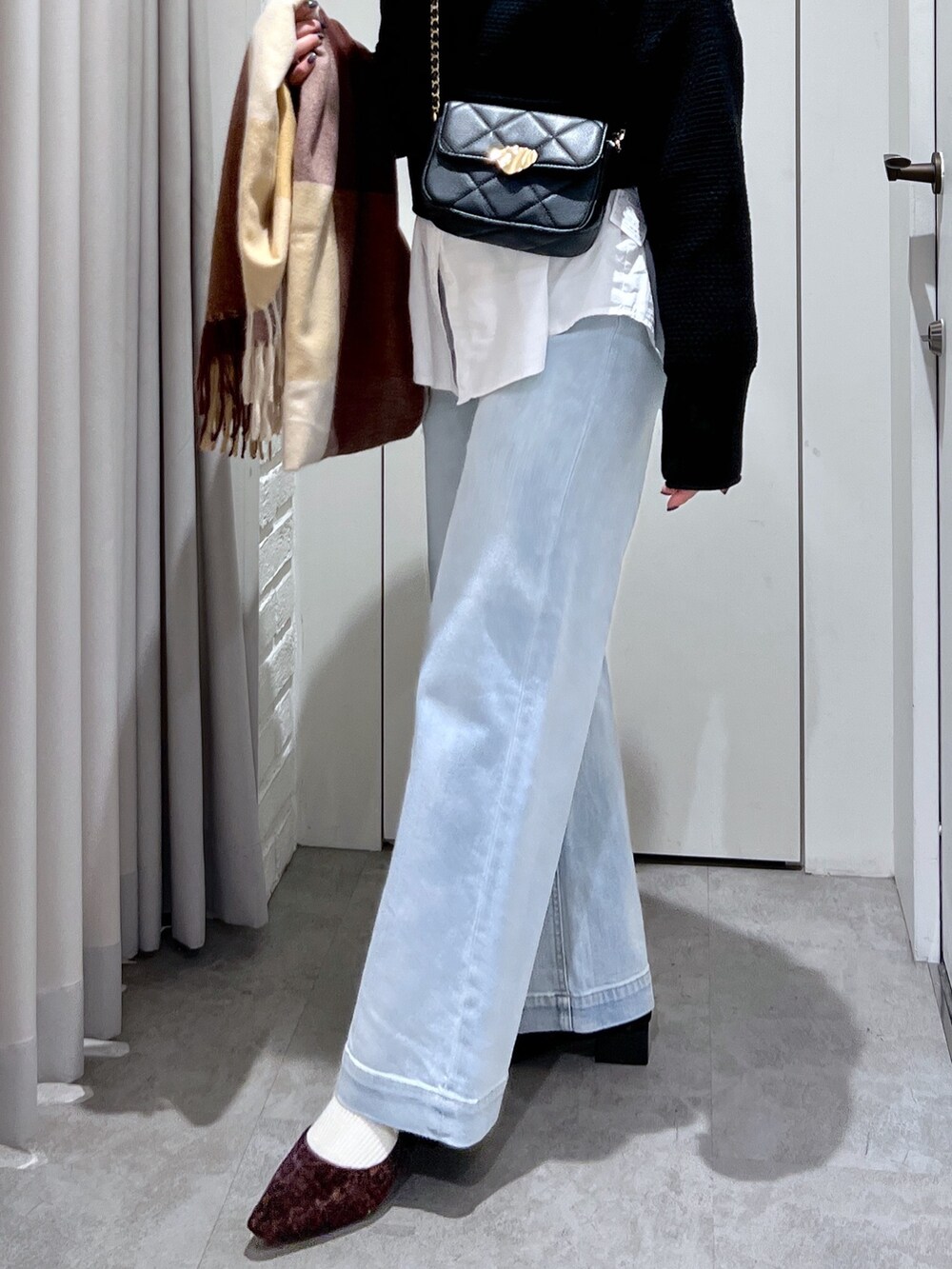 ブルー系のデニムパンツ、ブラック系のショルダーバッグ、ブラック系のニット/セーターを着用したレディースの冬コーディネートの6枚目の写真