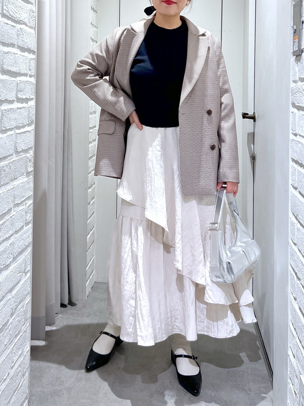ブラウン系のテーラードジャケット、ホワイト系のスカート、ブラック系のパンプスを着用したレディースの春コーディネートの5枚目の写真