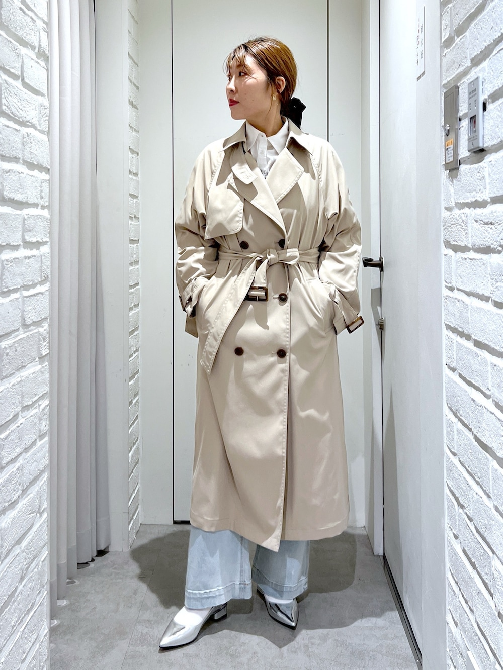 ベージュ系のトレンチコート、ブラック系のショルダーバッグ、ブルー系のデニムパンツを着用したレディースの春コーディネートの2枚目の写真