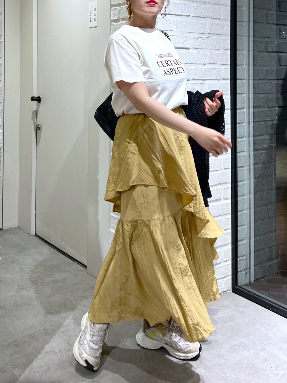 イエロー系のスカート、ブラック系のカーディガン/ボレロ、ホワイト系のTシャツ/カットソーを着用したレディースの夏コーディネートの5枚目の写真