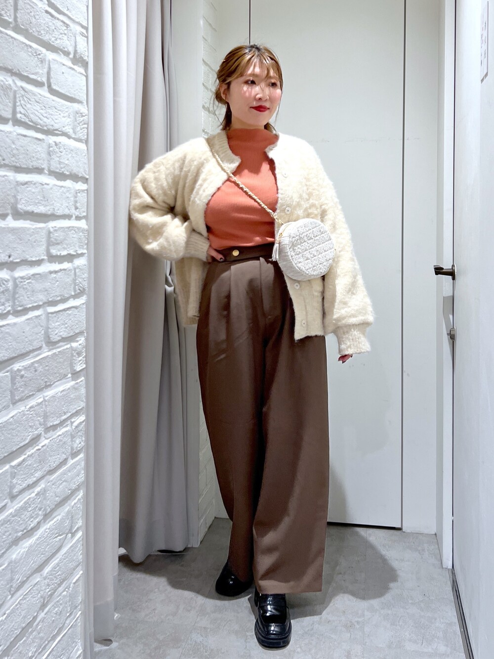 ブラウン系のスラックス、ベージュ系のニット/セーター、オレンジ系のニット/セーターを着用したレディースの秋コーディネートの4枚目の写真