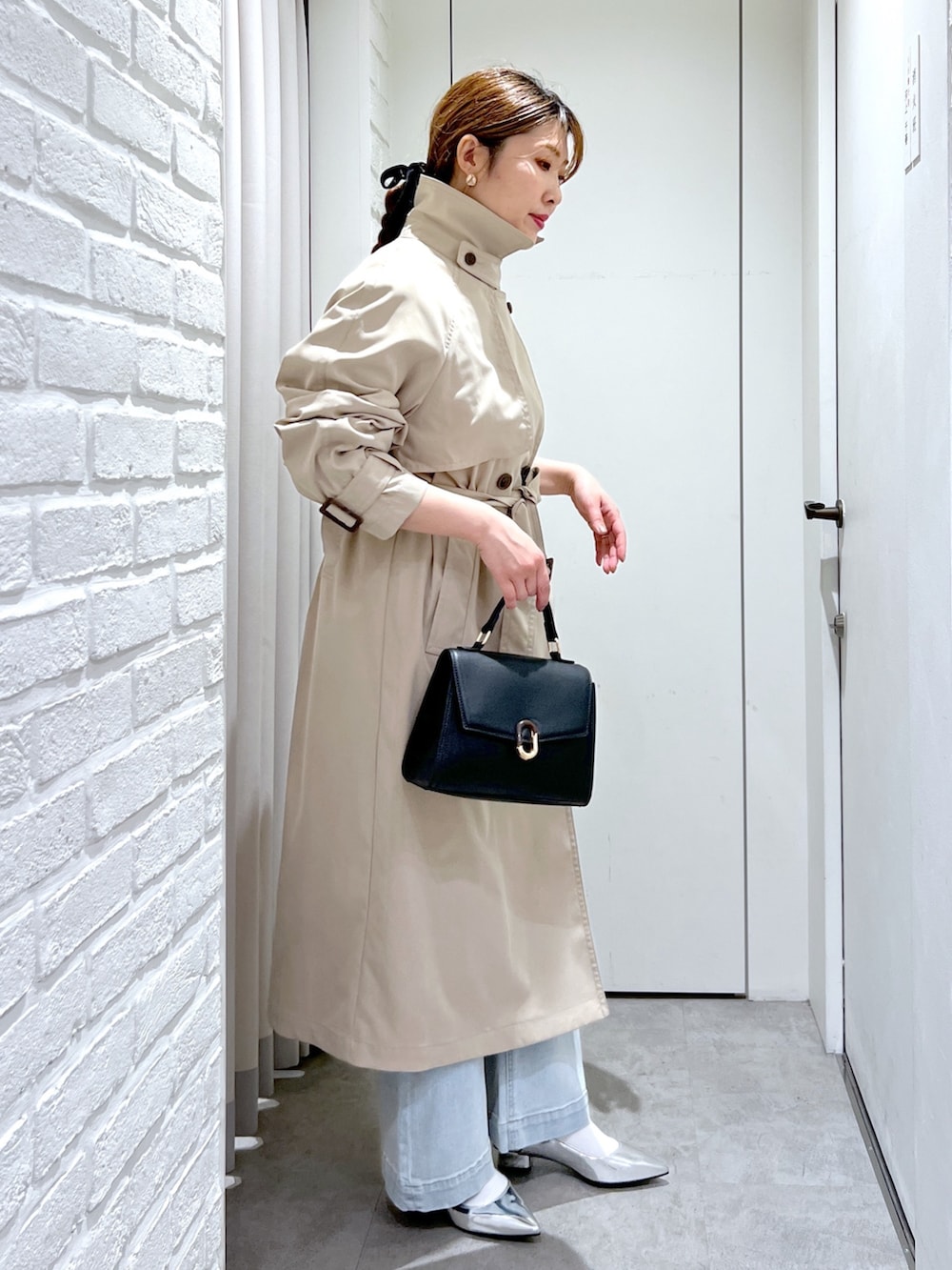 ベージュ系のトレンチコート、ブラック系のショルダーバッグ、ブルー系のデニムパンツを着用したレディースの春コーディネートの4枚目の写真