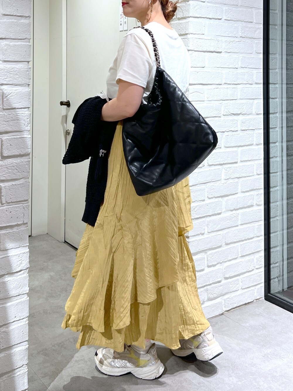 イエロー系のスカート、ブラック系のカーディガン/ボレロ、ホワイト系のTシャツ/カットソーを着用したレディースの夏コーディネートの4枚目の写真