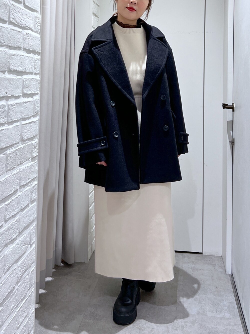 ブラック系のピーコート、ホワイト系のワンピース、ブラック系のTシャツ/カットソーを着用したレディースの冬コーディネートの5枚目の写真