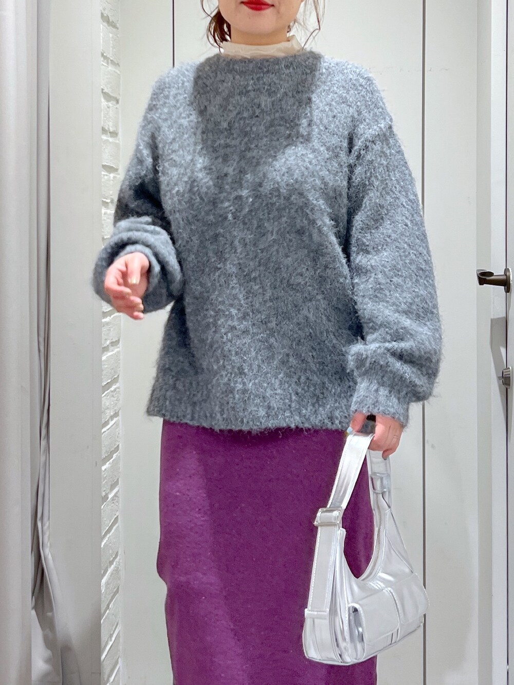 パープル系のスカート、グレー系のニット/セーター、ブラック系のブーツを着用したレディースの冬コーディネートの6枚目の写真