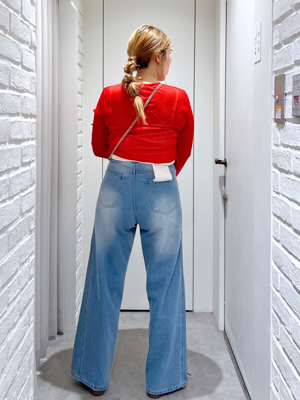 ブルー系のデニムパンツ、レッド系のカーディガン/ボレロ、ブラック系のショルダーバッグを着用したレディースの夏コーディネートの3枚目の写真