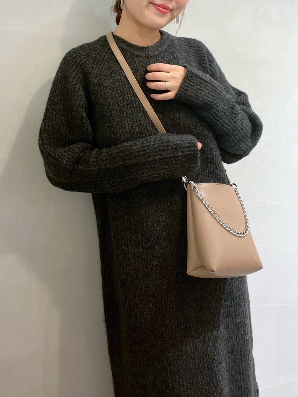 ブラック系のワンピース、ホワイト系のスニーカー、ベージュ系のショルダーバッグを着用したレディースの冬コーディネートの9枚目の写真