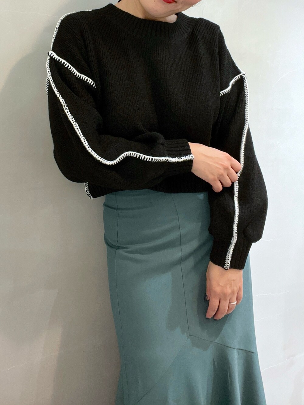 グリーン系のスカート、ブラック系のニット/セーター、ホワイト系のショルダーバッグを着用したレディースの冬コーディネートの7枚目の写真