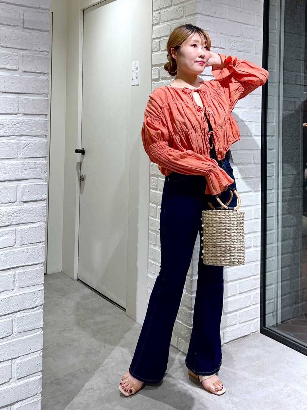 ブルー系のデニムパンツ、オレンジ系のシャツ/ブラウス、グレー系のサンダルを着用したレディースの夏コーディネートの2枚目の写真