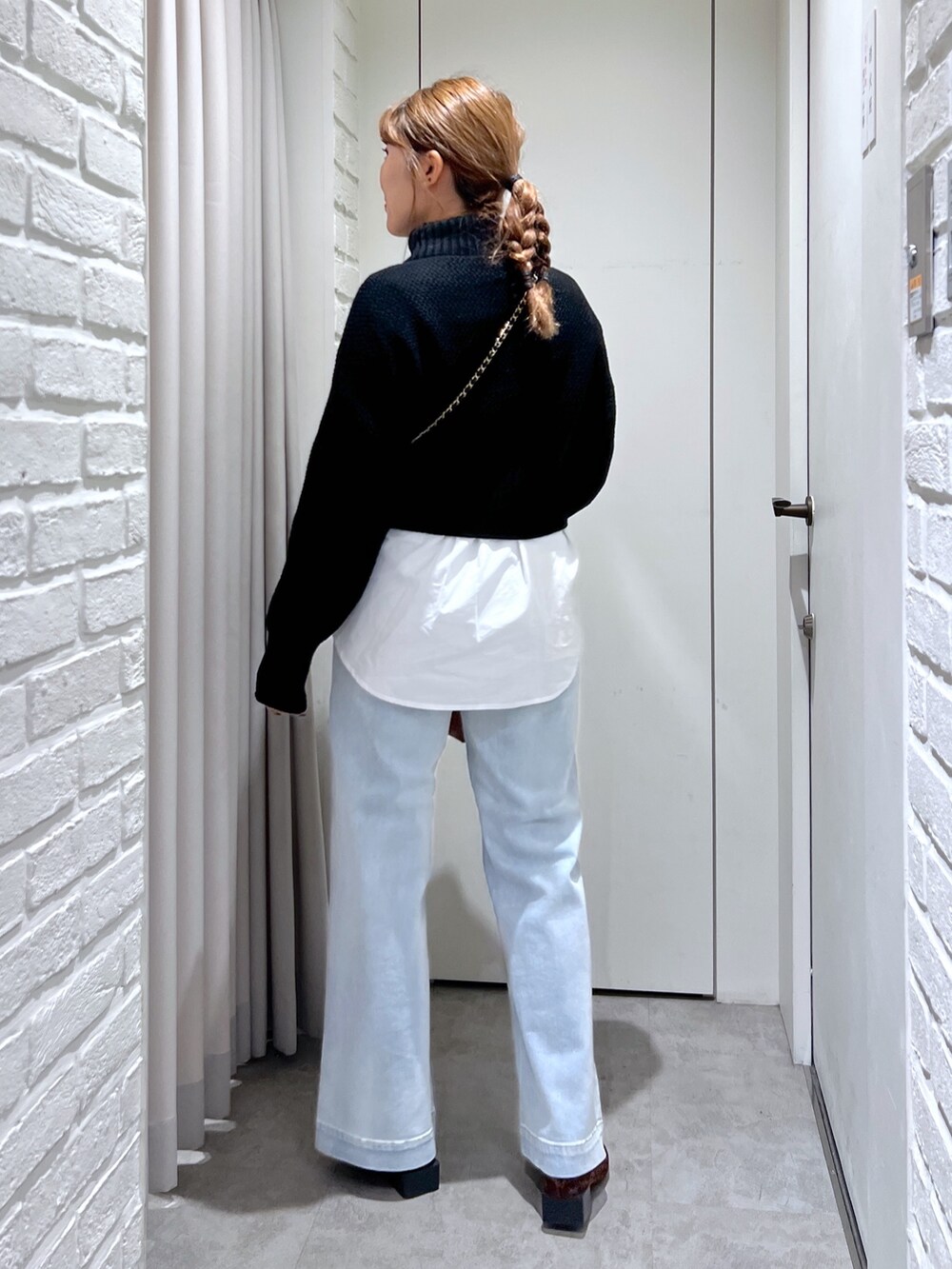 ブルー系のデニムパンツ、ブラック系のショルダーバッグ、ブラック系のニット/セーターを着用したレディースの冬コーディネートの4枚目の写真