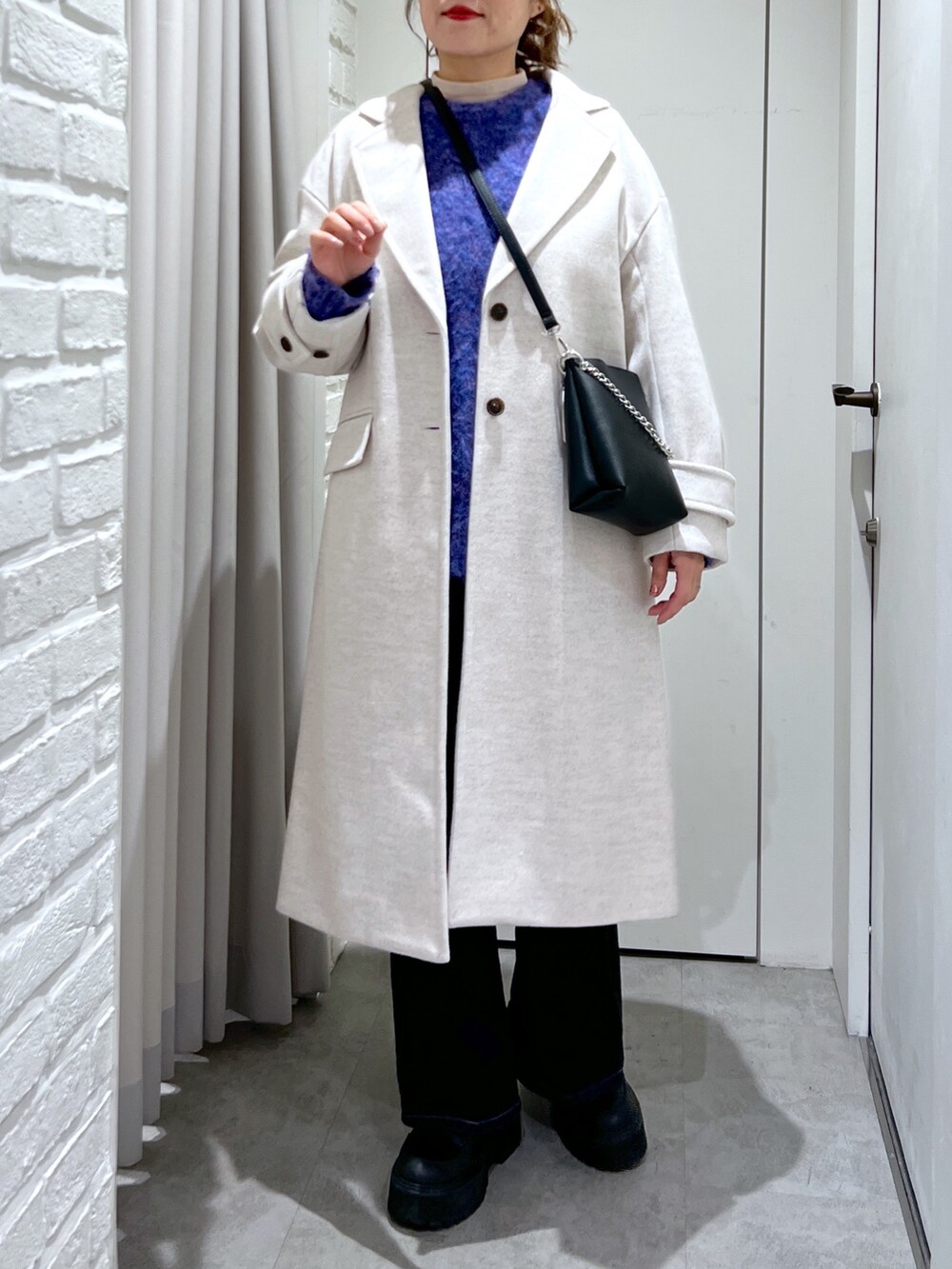 ベージュ系のチェスターコート、ブルー系のデニムパンツ、ブラック系のショルダーバッグを着用したレディースの冬コーディネートの5枚目の写真