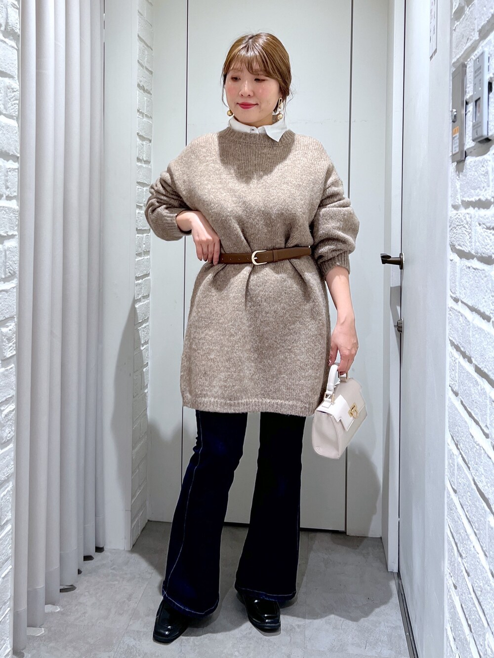 ブラウン系のワンピース、ホワイト系のショルダーバッグ、ブラック系のローファーを着用したレディースの冬コーディネートの2枚目の写真