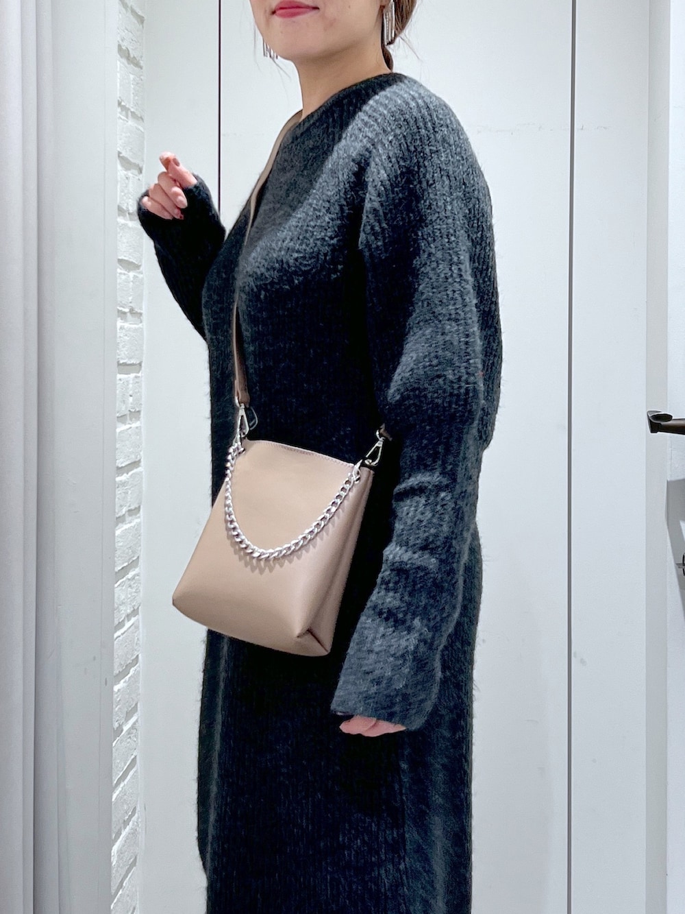 ブラック系のワンピース、ホワイト系のスニーカー、ベージュ系のショルダーバッグを着用したレディースの冬コーディネートの7枚目の写真