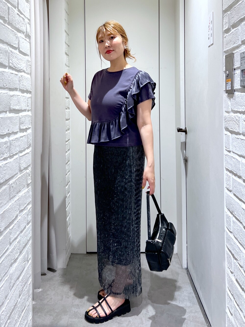 ブラック系のスカート、グレー系のTシャツ/カットソー、ブラック系のサンダルを着用したレディースの夏コーディネートの3枚目の写真