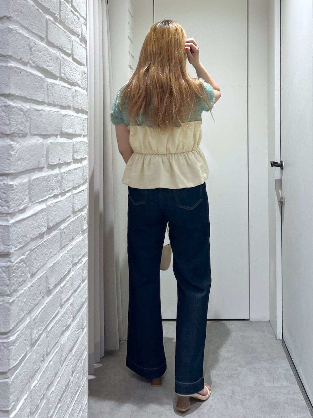 ブルー系のデニムパンツ、ベージュ系のトートバッグ、ホワイト系のシャツ/ブラウスを着用したレディースの夏コーディネートの4枚目の写真