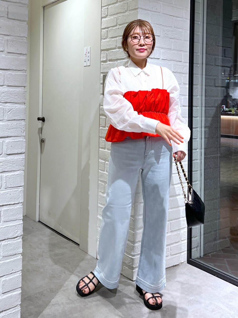 ブルー系のデニムパンツ、ブラック系のサンダル、レッド系のシャツ/ブラウスを着用したレディースの夏コーディネートの2枚目の写真