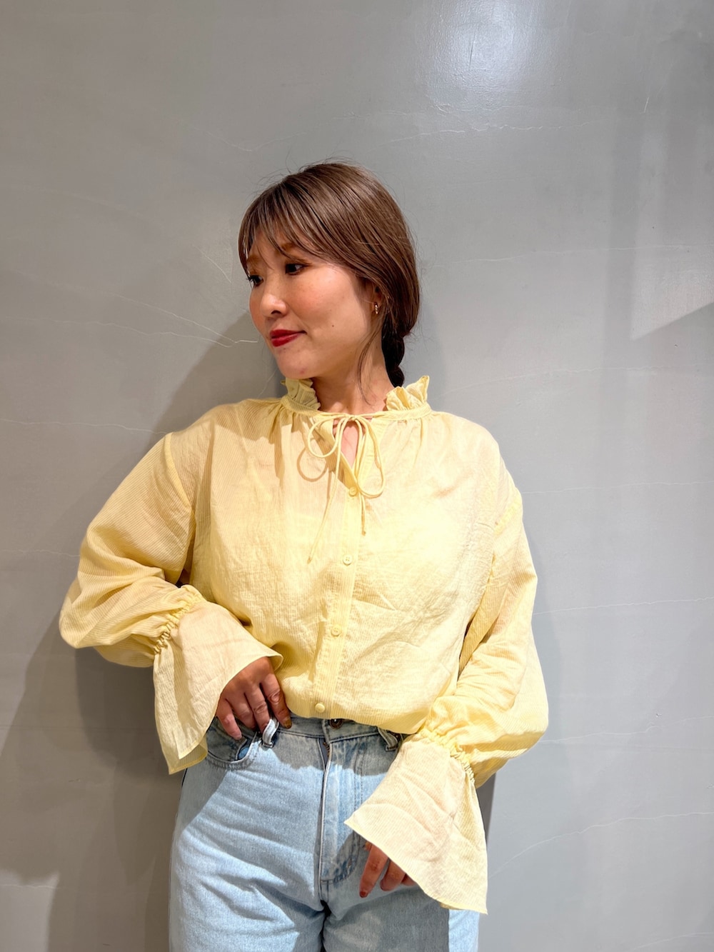 ブルー系のデニムパンツ、イエロー系のシャツ/ブラウス、ブラック系のショルダーバッグを着用したレディースの秋コーディネートの5枚目の写真