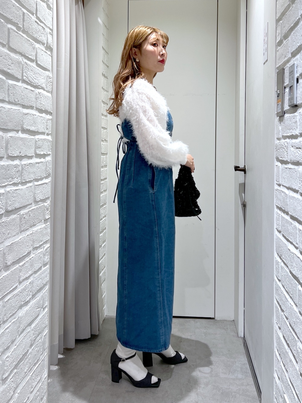 ブルー系のワンピース、ブラック系のサンダル、ブラック系のハンドバッグを着用したレディースの春コーディネートの2枚目の写真