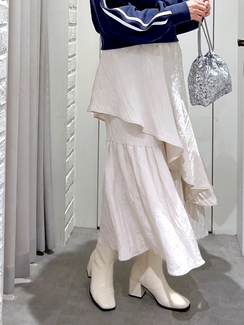 ホワイト系のスカート、ホワイト系のブーツ、シルバー系のハンドバッグを着用したレディースの春コーディネートの5枚目の写真