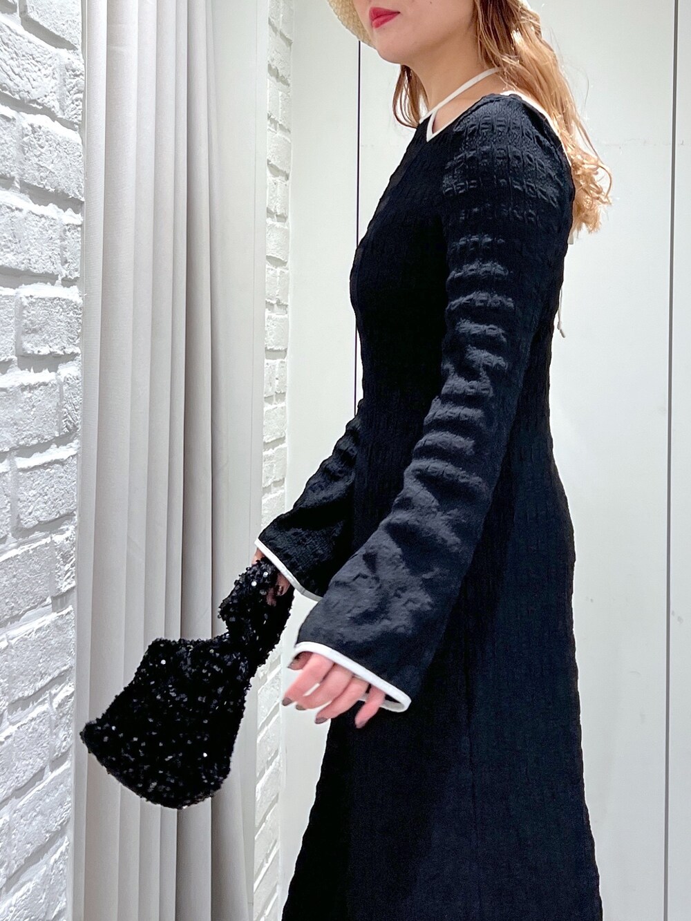 ブラック系のワンピース、ブルー系のデニムパンツ、ブラック系のハンドバッグを着用したレディースの春コーディネートの6枚目の写真