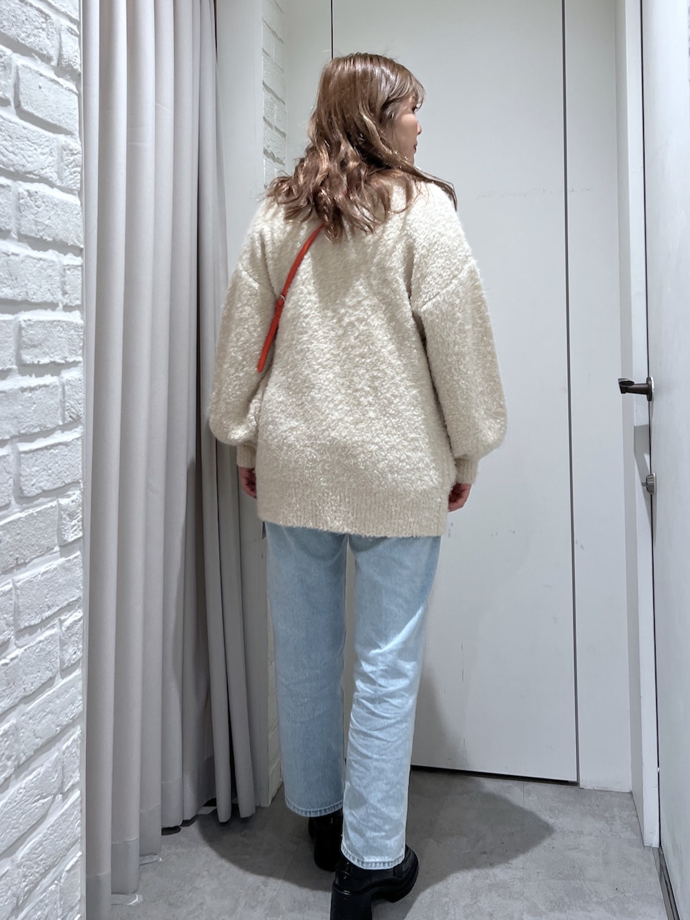 オレンジ系のショルダーバッグ、ブラック系のTシャツ/カットソー、ホワイト系のカーディガン/ボレロを着用したレディースの秋コーディネートの3枚目の写真