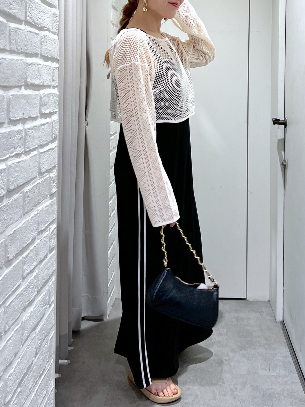 ブラック系のワンピース、ホワイト系のカーディガン/ボレロ、ブラック系のトートバッグを着用したレディースの夏コーディネートの6枚目の写真