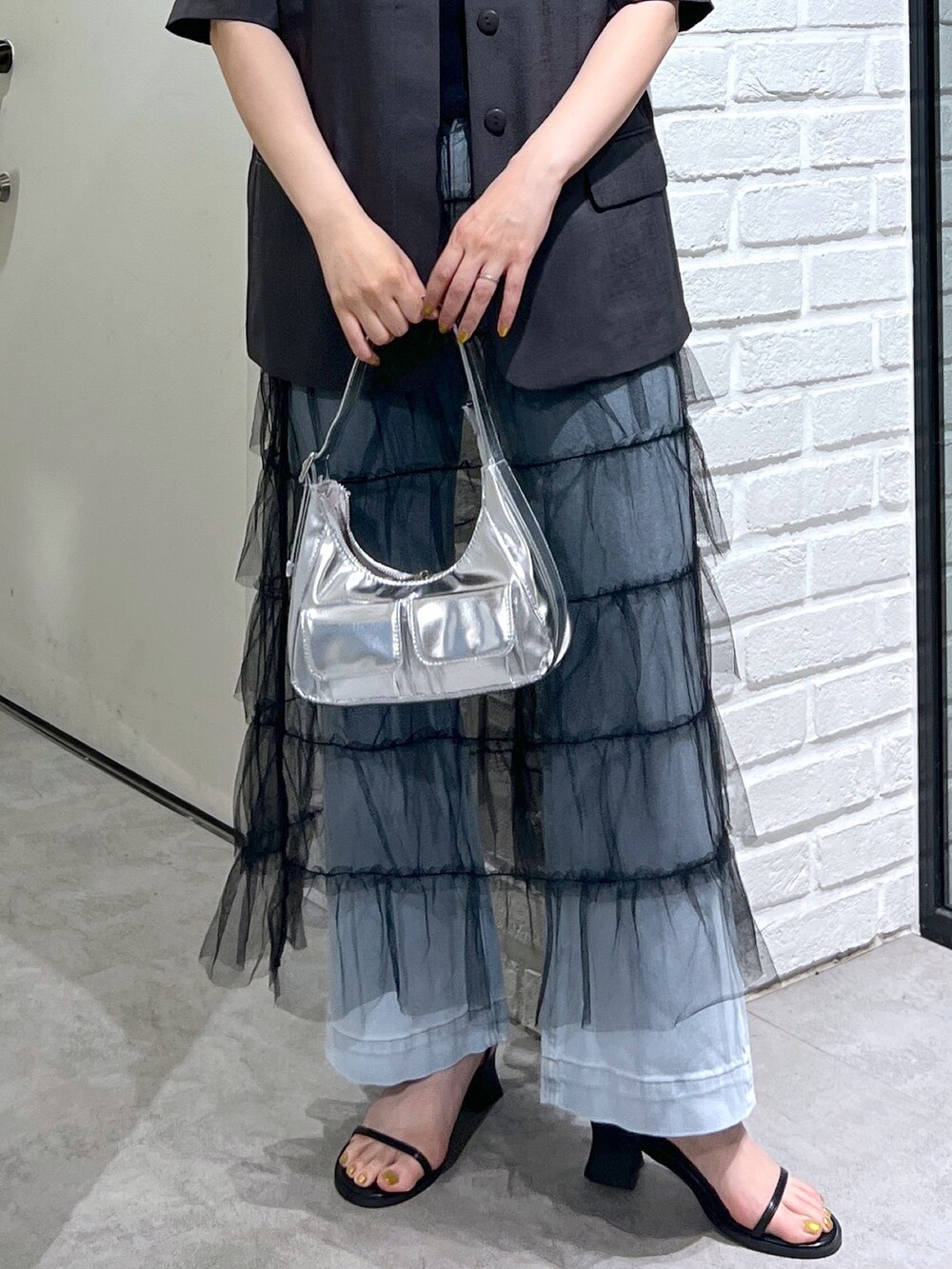 グレー系のノーカラージャケット、ブラック系のスカート、ブルー系のデニムパンツを着用したレディースの夏コーディネートの6枚目の写真